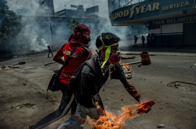 Jóvenes lanzan bombas molotov contra las fuerzas de seguridad, el miércoles en Caracas. Credit Meridith Kohut para The New York Times
