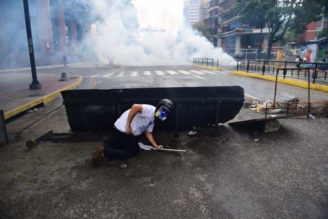 Demonstrators clash with the riot police during a protest against Venezuelan President Nicolas Maduro, in Caracas on April 20, 2017. Venezuelan riot police fired tear gas Thursday at groups of protesters seeking to oust President Nicolas Maduro, who have vowed new mass marches after a day of deadly unrest. Police in western Caracas broke up scores of opposition protesters trying to join a larger march, though there was no immediate repeat of Wednesday's violent clashes, which left three people dead. / AFP PHOTO / RONALDO SCHEMIDT