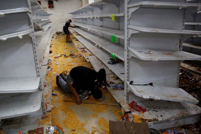 Workers look for valuables among the damaged goods in a supermarket, after it was looted in Caracas, Venezuela April 21, 2017. REUTERS/Carlos Garcia Rawlins