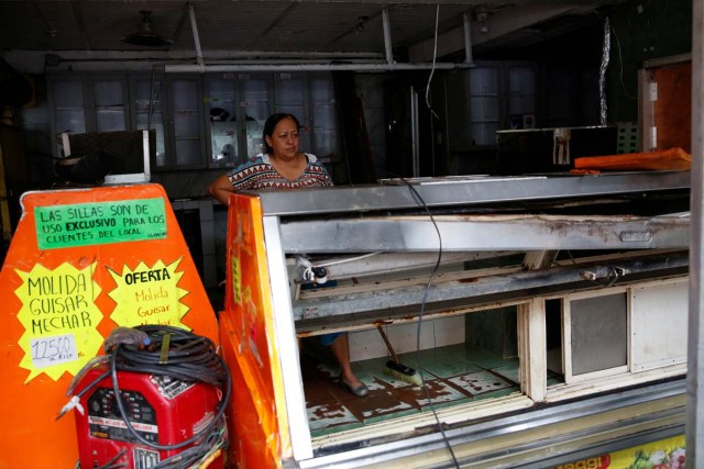 A woman stand next to broken refrigerators, after a butcher's stall was looted in Caracas, Venezuela April 21, 2017. REUTERS/Carlos Garcia Rawlins