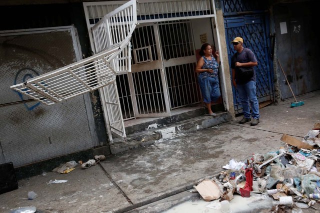 People talk next to the broken fences of a stall after it was looted in Caracas, Venezuela April 21, 2017. REUTERS/Carlos Garcia Rawlins