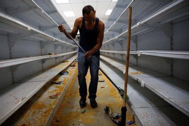 A worker cleans the shelves in a supermarket after it was looted in Caracas, Venezuela April 21, 2017. REUTERS/Carlos Garcia Rawlins