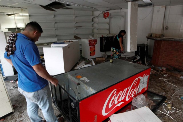 A worker looks for valuables scattered in the damaged goods in a convenience store, after it was looted in Caracas, Venezuela April 21, 2017. REUTERS/Christian Veron