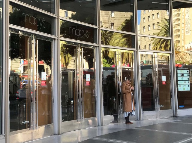 An employee stands outside the closed doors of Macy's department store, during a power cut in San Francisco, California, U.S. April 21, 2017. REUTERS/Alexandria Sage