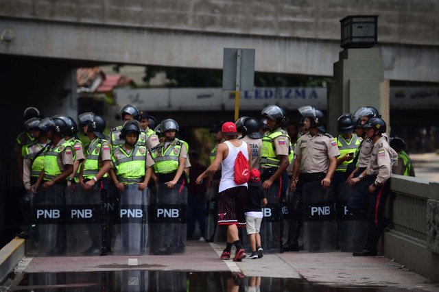 Venezuelan police in riot gear remain on standby in Caracas, on April 22, 2017. Venezuelans gathered Saturday for "silent marches" against President Nicolas Maduro, a test of his government's tolerance for peaceful protests after three weeks of violent unrest that has left 20 people dead. / AFP PHOTO / RONALDO SCHEMIDT