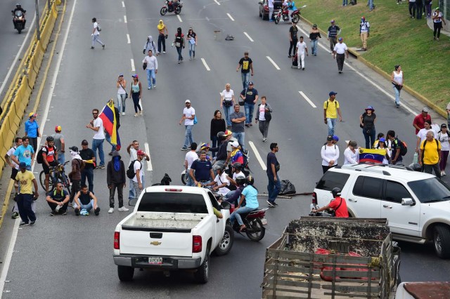 Venezuelan opposition activists block the Francisco Fajardo motorway in Caracas, on April 24, 2017. Protesters plan Monday to block Venezuela's main roads including the capital's biggest motorway, triggering fears of further violence after three weeks of unrest left 21 people dead. / AFP PHOTO / RONALDO SCHEMIDT