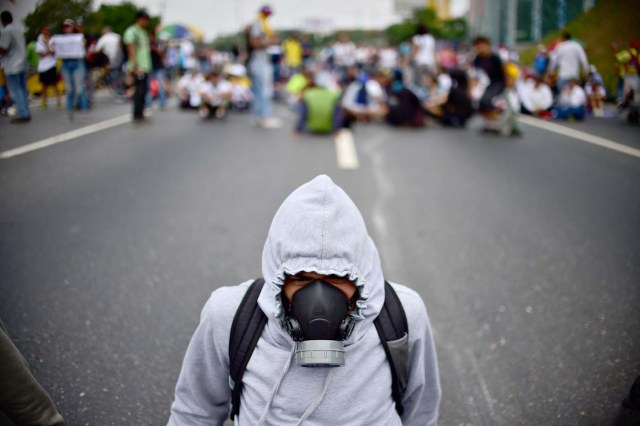 Venezuelan opposition activists block organize a sit-in to block the Francisco Fajardo motorway in Caracas, on April 24, 2017. Protesters plan Monday to block Venezuela's main roads including the capital's biggest motorway, triggering fears of further violence after three weeks of unrest left 21 people dead. / AFP PHOTO / RONALDO SCHEMIDT