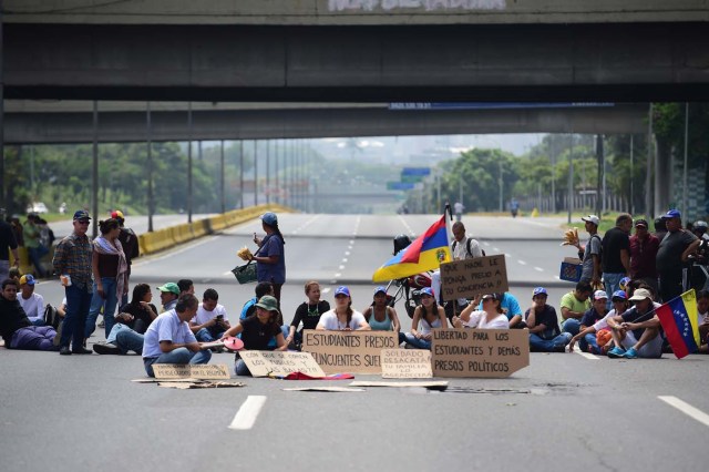 Venezuelan opposition activists block organize a sit-in to block the Francisco Fajardo motorway in Caracas, on April 24, 2017. Protesters plan Monday to block Venezuela's main roads including the capital's biggest motorway, triggering fears of further violence after three weeks of unrest left 21 people dead. / AFP PHOTO / RONALDO SCHEMIDT
