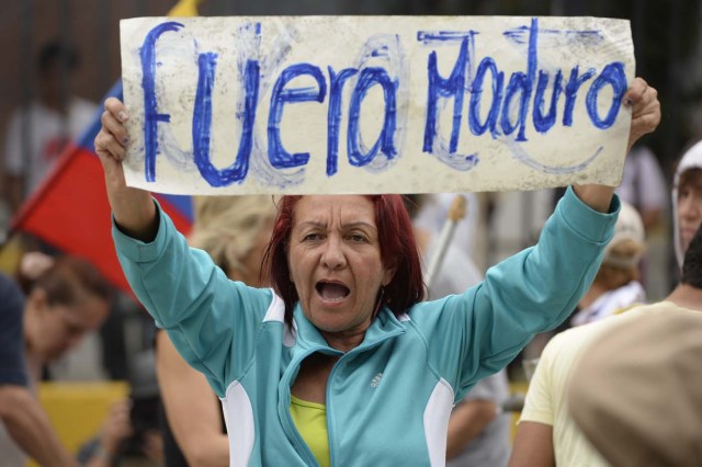 A Venezuelan opposition activist participating in a rally to block an avenue holds a placard that reads "Get Out Maduro", in Caracas, on April 24, 2017. Protesters plan Monday to block Venezuela's main roads including the capital's biggest motorway, triggering fears of further violence after three weeks of unrest left 21 people dead. / AFP PHOTO / FEDERICO PARRA
