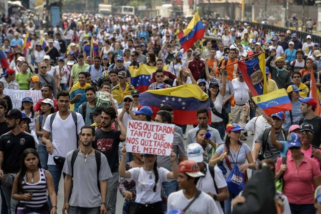 Venezuelan opposition activists march in Caracas, on April 24, 2017. Protesters plan Monday to block Venezuela's main roads including the capital's biggest motorway, triggering fears of further violence after three weeks of unrest left 21 people dead. / AFP PHOTO / FEDERICO PARRA