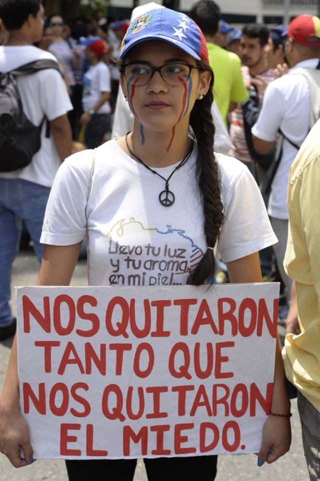A Venezuelan opposition activist participating in a rally to block an avenue holds a placard that reads "They Took Away So Many Things From Us That They Also Took The Fear", in Caracas, on April 24, 2017. Protesters plan Monday to block Venezuela's main roads including the capital's biggest motorway, triggering fears of further violence after three weeks of unrest left 21 people dead. / AFP PHOTO / FEDERICO PARRA