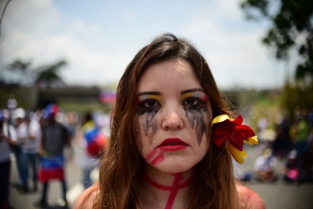 A Venezuelan opposition activist participates in a sit-in to block the Francisco Fajardo motorway in Caracas, on April 24, 2017. Protesters plan Monday to block Venezuela's main roads including the capital's biggest motorway, triggering fears of further violence after three weeks of unrest left 21 people dead. / AFP PHOTO / RONALDO SCHEMIDT