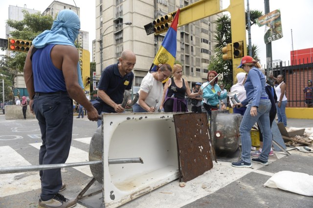 Venezuelan opposition activists set up a barricade to block an avenue in Caracas, on April 24, 2017. Protesters plan Monday to block Venezuela's main roads including the capital's biggest motorway, triggering fears of further violence after three weeks of unrest left 21 people dead. / AFP PHOTO / FEDERICO PARRA