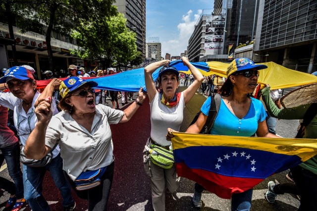 Venezuelan opposition activists march against President Nicolas Maduro in Caracas, on April 24, 2017. Protesters rallied on Monday vowing to block Venezuela's main roads to raise pressure on Maduro after three weeks of deadly unrest that have left 21 people dead. Riot police fired rubber bullets and tear gas to break up one of the first rallies in eastern Caracas early Monday while other groups were gathering elsewhere, the opposition said.  / AFP PHOTO / Juan BARRETO