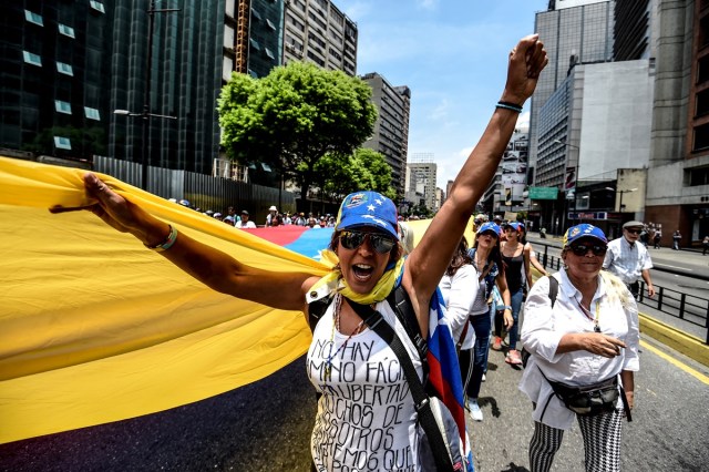 Venezuelan opposition activists march against President Nicolas Maduro in Caracas, on April 24, 2017. Protesters rallied on Monday vowing to block Venezuela's main roads to raise pressure on Maduro after three weeks of deadly unrest that have left 21 people dead. Riot police fired rubber bullets and tear gas to break up one of the first rallies in eastern Caracas early Monday while other groups were gathering elsewhere, the opposition said.  / AFP PHOTO / Juan BARRETO