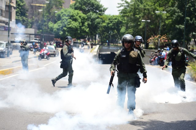 Riot police charge amid a cloud of tear gas on opponents of Venezuelan President Nicolas Maduro marching in Caracas on April 26, 2017. Protesters in Venezuela plan a high-risk march against President Maduro Wednesday, sparking fears of fresh violence after demonstrations that have left 26 dead in the crisis-wracked country. / AFP PHOTO / RONALDO SCHEMIDT