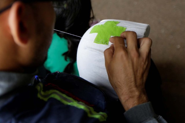 A volunteer sews a green cross to his helmet while he waits for the planning of the day to help injured demonstrators in Caracas, Venezuela April 22, 2017. Picture taken April 22, 2017. REUTERS/Marco Bello