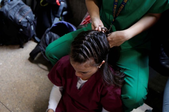 A volunteer has her hair made by a fellow volunteer while they wait for the planning of the day to help injured demonstrators in Caracas, Venezuela April 22, 2017. Picture taken April 22, 2017. REUTERS/Marco Bello