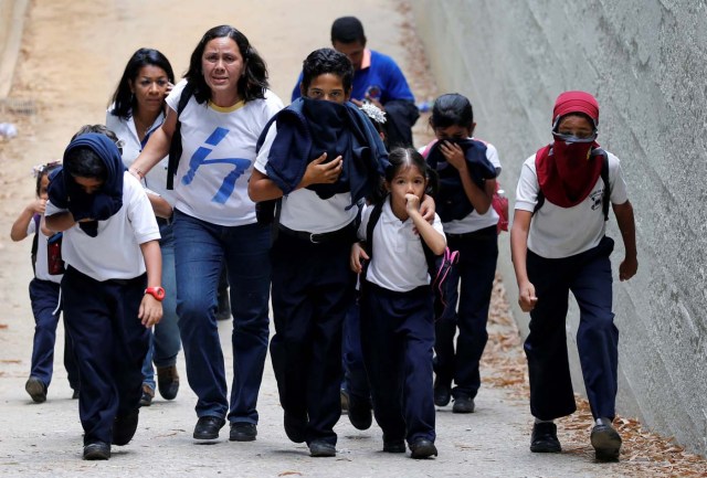 School children protect themselves from tear gas during a rally against Venezuela's President Nicolas Maduro in Caracas, Venezuela April 26, 2017. REUTERS/Carlos Garcia Rawlins