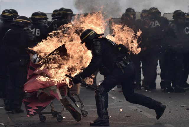 Protesters launch a burning trolley towards French CRS anti-riot police officers during a march for the annual May Day workers' rally in Paris on May 1, 2017. / AFP PHOTO / PHILIPPE LOPEZ