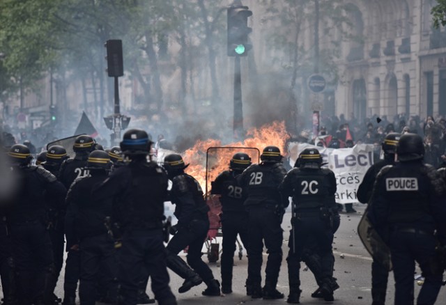 Protesters launch a burning trolley towards French CRS anti-riot police officers during a march for the annual May Day workers' rally in Paris on May 1, 2017. / AFP PHOTO / PHILIPPE LOPEZ