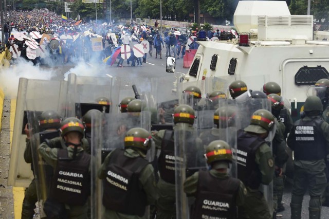 Riot police and demonstrators clash during a protest against Venezuelan President Nicolas Maduro, in Caracas on May 3, 2017. Venezuela's angry opposition rallied Wednesday vowing huge street protests against President Nicolas Maduro's plan to rewrite the constitution and accusing him of dodging elections to cling to power despite deadly unrest. / AFP PHOTO / RONALDO SCHEMIDT