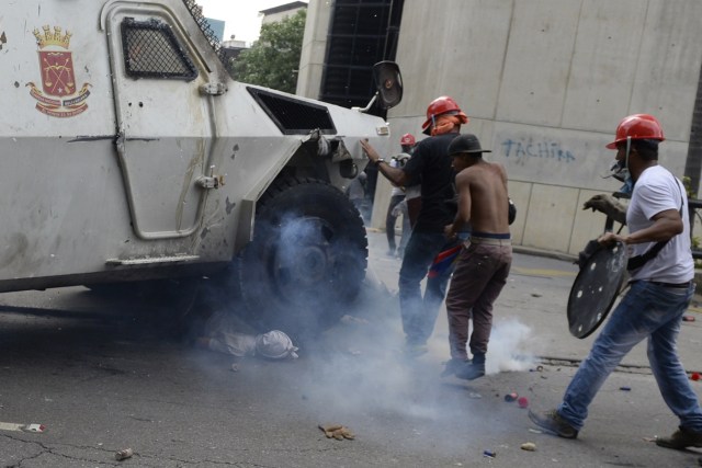 A Venezuelan National Guard riot control vehicle runs over an opposition demonstrator during a protest against Venezuelan President Nicolas Maduro, in Caracas on May 3, 2017. Venezuela's angry opposition rallied Wednesday vowing huge street protests against President Nicolas Maduro's plan to rewrite the constitution and accusing him of dodging elections to cling to power despite deadly unrest. / AFP PHOTO / FEDERICO PARRA / GRAPHIC CONTENT