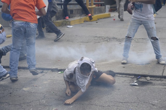 An opposition demonstrator ran over by a National Guard control vehicle tries to sit up during a protest against Venezuelan President Nicolas Maduro, in Caracas on May 3, 2017. Venezuela's angry opposition rallied Wednesday vowing huge street protests against President Nicolas Maduro's plan to rewrite the constitution and accusing him of dodging elections to cling to power despite deadly unrest. / AFP PHOTO / FEDERICO PARRA / GRAPHIC CONTENT