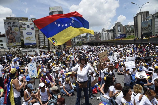 Venezuelan opposition activists take part in a women's march aimed to keep pressure on President Nicolas Maduro, whose authority is being increasingly challenged by protests and deadly unrest, in Caracas on May 6, 2017. The death toll since April, when the protests intensified after Maduro's administration and the courts stepped up efforts to undermine the opposition, is at least 36 according to prosecutors. / AFP PHOTO / JUAN BARRETO