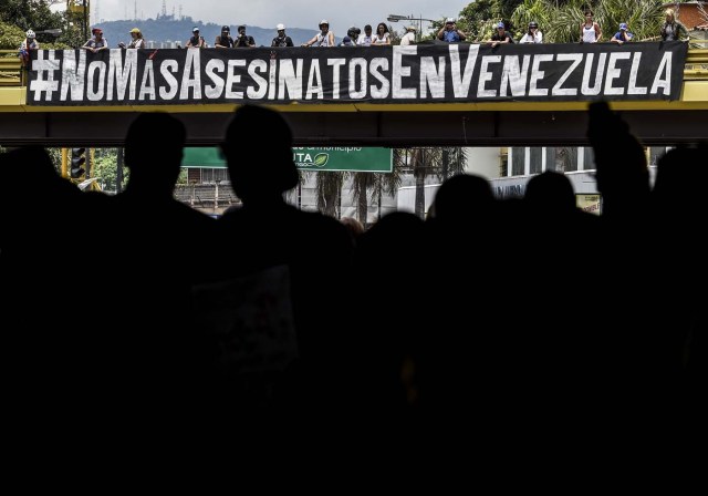 View of a banner reading #NoMoreKillingsInVenezuela during a demonstration in rejection of the recent deaths of young people by security forces -within opposition protests- in Caracas on May 7, 2017. The last death in Venezuela's unrest, of a 22-year-old man, occurred during looting in Valencia, one of Venezuelan cities hardest hit by a worsening economic crisis. Demonstrators blame Maduro for the country's plight and the shortages of food and medicine, and demand elections to remove the leftist president.  / AFP PHOTO / JUAN BARRETO