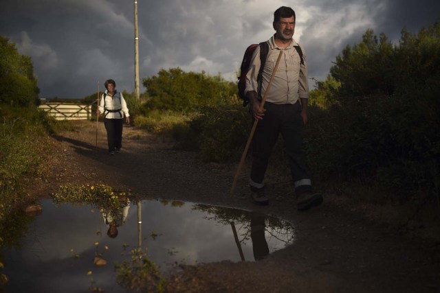 Carlos Gil (R) and his sister Maria Jose (L), 50 years old, walk on the morning they started their walk to Fatima, in Cascais, outskirts of Lisbon, on May 5, 2017.  Carlos Gil is a payer-off of promises, at least that is the way the Roman Catholic refers to himself. But he is more commonly known as a rent-a-pilgrim. This 52-year-old Portuguese national takes on pilgrimages by proxy (in the name of others), especially Catholics unable to fulfil the journey because of sickness or too busy or lazy to undertake the week-long spiritual walk to the central Portuguese town of Fatima. He can be hired for an average cost of 2,500 euros. / AFP PHOTO / PATRICIA DE MELO MOREIRA / TO GO WITH AFP STORY BY BRIGITTE HAGEMANN