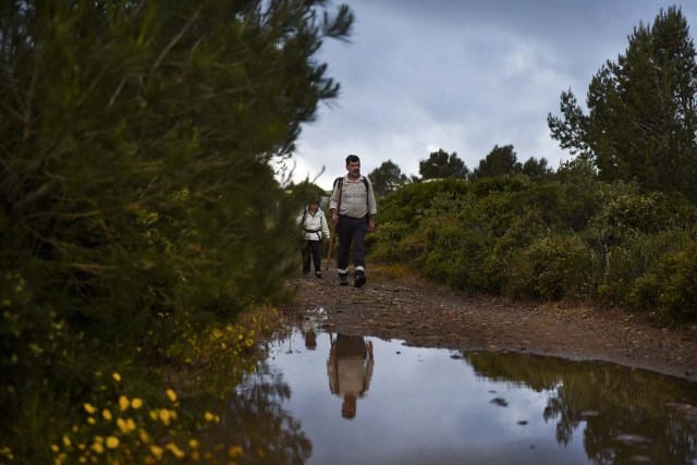 Carlos Gil (R) and his sister Maria Jose (L), 50 years old, walk on the morning they started their walk to Fatima, in Cascais, outskirts of Lisbon, on May 5, 2017.  Carlos Gil is a payer-off of promises, at least that is the way the Roman Catholic refers to himself. But he is more commonly known as a rent-a-pilgrim. This 52-year-old Portuguese national takes on pilgrimages by proxy (in the name of others), especially Catholics unable to fulfil the journey because of sickness or too busy or lazy to undertake the week-long spiritual walk to the central Portuguese town of Fatima. He can be hired for an average cost of 2,500 euros. / AFP PHOTO / PATRICIA DE MELO MOREIRA / TO GO WITH AFP STORY BY BRIGITTE HAGEMANN
