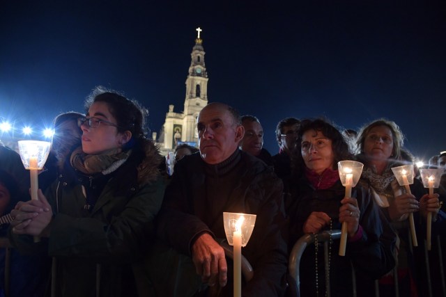 Pilgrims holds candles during the Blessing for the Candles from the Chapel of the Apparitions by Pope Francis, in Fatima on May 12, 2017. Two of the three child shepherds who reported apparitions of the Virgin Mary in Fatima, Portugal, one century ago, will be declared saints on May 13, 2017 by Pope Francis. The canonisation of Jacinta and Francisco Marto will take place during the Argentinian pontiff's visit to a Catholic shrine visited by millions of pilgrims every year. / AFP PHOTO / Tiziana FABI