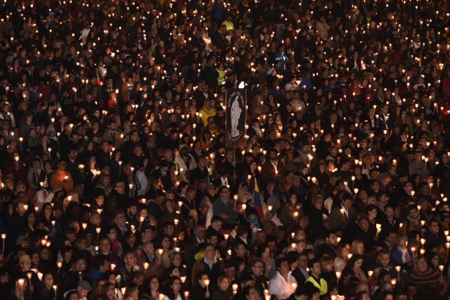 Pilgrims hold candles at the Shrine of Fatima during the Blessing for the Candles from the Chapel of the Apparitions by Pope Francis, in Fatima on May 12, 2017. Two of the three child shepherds who reported apparitions of the Virgin Mary in Fatima, Portugal, one century ago, will be declared saints on May 13, 2017 by Pope Francis. The canonisation of Jacinta and Francisco Marto will take place during the Argentinian pontiff's visit to a Catholic shrine visited by millions of pilgrims every year. / AFP PHOTO / TIZIANA FABI