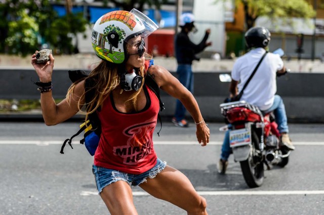 (FILES) This file photo taken on May 01, 2017 shows an opposition activist throwing a stone during a march against Venezuelan President Nicolas Maduro held on May Day, in Caracas on May 1, 2017. "That is me all over, the strength and the passion," Ciarcelluti, 44, told AFP. "I never run out of energy." She says she hopes to be "an inspiration" to other protesters. "We are getting there," she says. / AFP PHOTO / FEDERICO PARRA