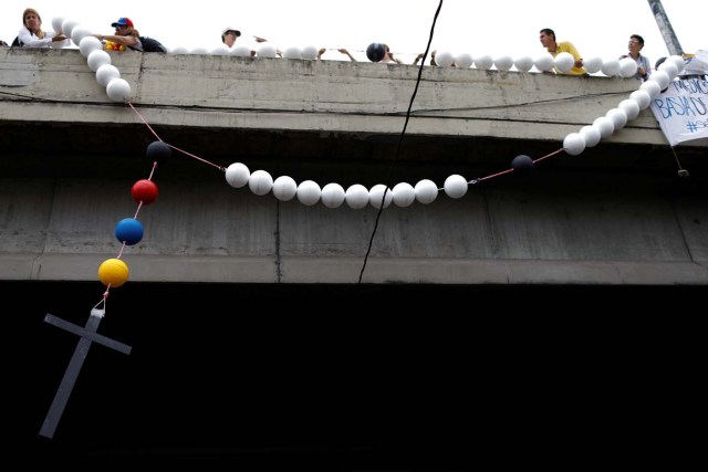 Opposition supporters hang a giant rosary beads from a bridge as they block a highway, during a protest against Venezuelan President Nicolas Maduro's government in Caracas, Venezuela May 15, 2017. REUTERS/Carlos Garcia Rawlins