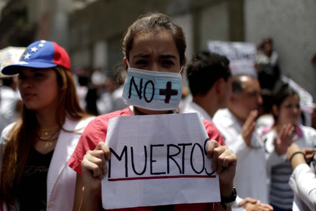 A woman wears a mask and a banner that read "No more deaths" as she takes part in a rally of workers of the health sector against President Nicolas Maduro's government in Caracas, Venezuela May 17, 2017. REUTERS/Marco Bello