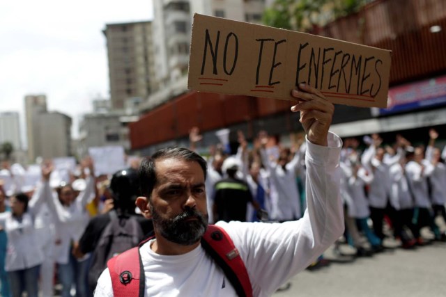 A man holds a banner that reads "Do not get sick" as he takes part in a rally of workers of the health sector against President Nicolas Maduro's government in Caracas, Venezuela May 17, 2017. REUTERS/Marco Bello