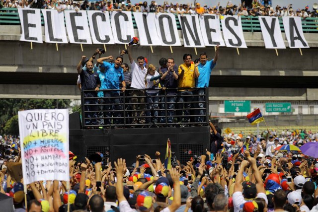 Venezuelan opposition leader and Governor of Miranda state Henrique Capriles (3L) and Lilian Tintori (4R), wife of jailed opposition leader Leopoldo Lopez, participate in a rally against President Nicolas Maduro in front of a banner that reads "Elections now" in Caracas, Venezuela, May 20, 2017. REUTERS/Carlos Barria
