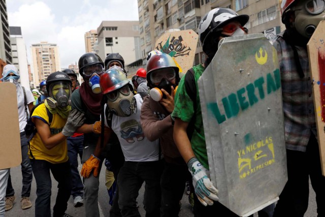 Demonstrators take cover behind a home-made shield with the word "freedom" on it while clashing with riot security forces during a rally against President Nicolas Maduro in Caracas, Venezuela May 24, 2017. REUTERS/Carlos Garcia Rawlins