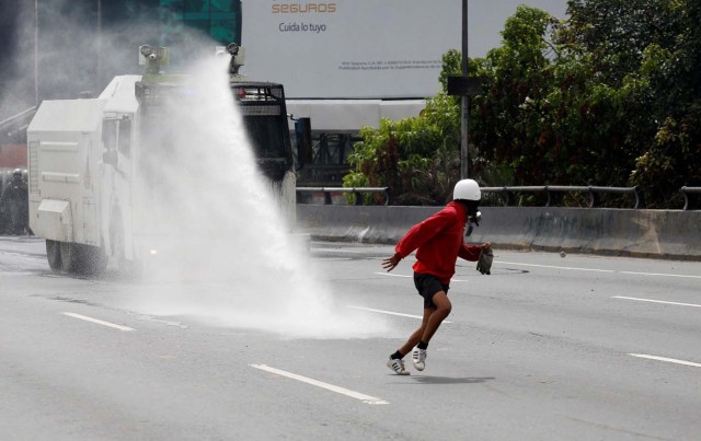 A demonstrator runs away from a water canon while clashing with riot security forces during a rally against President Nicolas Maduro in Caracas, Venezuela, May 24, 2017. REUTERS/Marco Bello