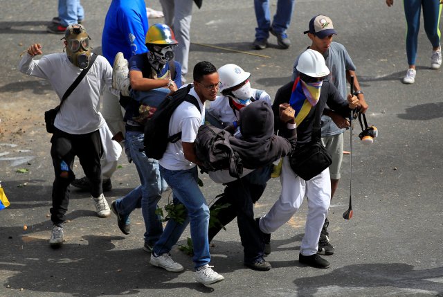 Escuderos libertarios rescatan a uno de los heridos durante las manifestaciones antigubernamentales de este miércoles. REUTERS/Christian Veron