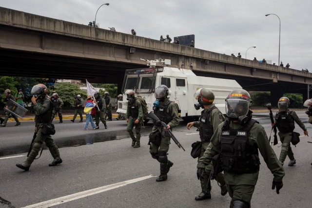 CAR010. CARACAS (VENEZUELA), 03/05/2017 - Militares intentan retirar a una mujer que bloquea el paso de una tanqueta de la Guardia Nacional durante una manifestación encabezada por diputados opositores hoy, miércoles 3 de mayo de 2017, en Caracas (Venezuela). La Guardia Nacional Bolivariana (GNB, policía militarizada) de Venezuela dispersó hoy con gases lacrimógenos una movilización opositora en el este de Caracas que pretendía llegar hasta la sede de la Asamblea Nacional (AN, Parlamento), ubicada en el centro de la capital. EFE/MIGUEL GUTIERREZ
