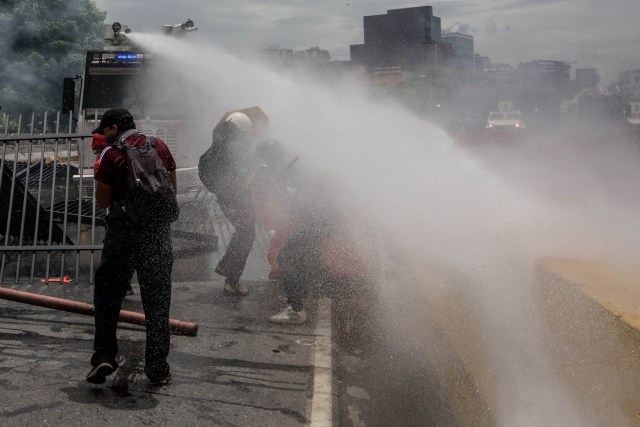 CAR023. CARACAS (VENEZUELA), 03/05/2017 - Miembros de la Guardia Bolivariana lanzan un chorro de agua a presión a un grupo de manifestantes hoy, miércoles 3 de mayo de 2017, en Caracas (Venezuela). La Guardia Nacional Bolivariana (GNB, policía militarizada) de Venezuela dispersó hoy con gases lacrimógenos una movilización opositora en el este de Caracas que pretendía llegar hasta la sede de la Asamblea Nacional (AN, Parlamento), ubicada en el centro de la capital. EFE/MIGUEL GUTIERREZ