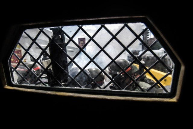 View from inside a National Guard riot control vehicle of riot police on stand by as opposition demonstrators protest in Caracas, on May 31, 2017. Venezuelan authorities on Wednesday began signing up candidates for a planned constitutional reform body, a move that has inflamed deadly unrest stemming from anti-government protests. / AFP PHOTO / JUAN BARRETO