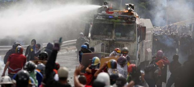 Demonstrator run aways from a water cannon vehicle during clashes while rallying against Venezuela's President Nicolas Maduro in Caracas, Venezuela May 22, 2017. REUTERS/Marco Bello