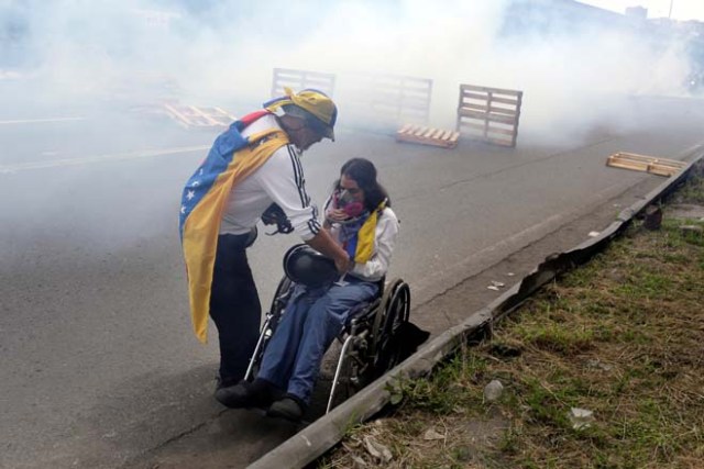 A man helps a woman on a wheelchair during clashes with riots police at a rally called by health care workers and opposition activists against Venezuela's President Nicolas Maduro in Caracas, Venezuela May 22, 2017. REUTERS/Marco Bello