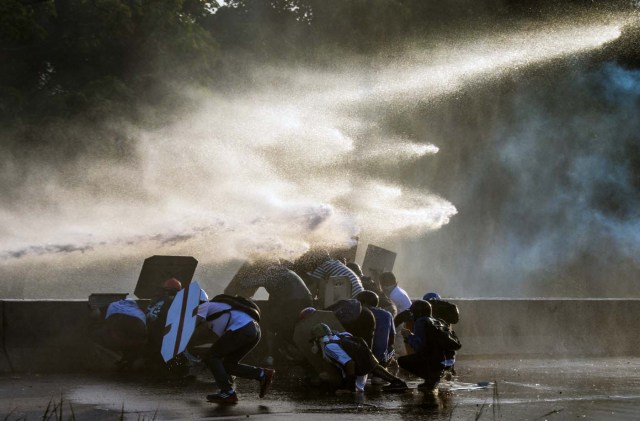Venezuelan opposition activists clash with the riot police during a rally against the government of President Nicolas Maduro, in Caracas, on May 18, 2017. Venezuelan opposition leader Henrique Capriles said Thursday authorities confiscated his passport and prevented him from travelling to New York to discuss his country's deadly political crisis with United Nations officials. On Monday Venezuelans launched a seventh week of anti-government demonstrations by blocking roads, vowing not to budge all day in protest at a deadly political and economic crisis. / AFP PHOTO / FEDERICO PARRA