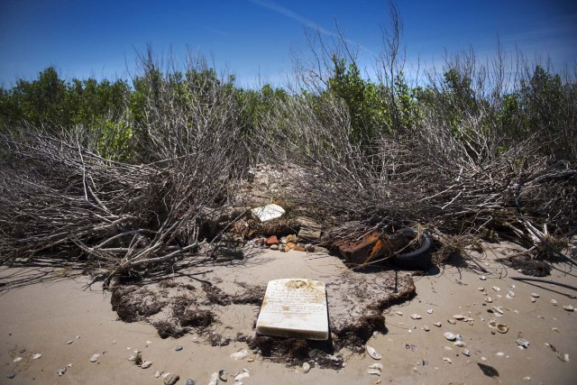 A grave stone rests on the beach where a cemetery once stood but has been washed away due to erosion in an area called Canaan in Tangier, Virginia, May 16, 2017, where climate change and rising sea levels threaten the inhabitants of the slowly sinking island. Now measuring 1.2 square miles, Tangier Island has lost two-thirds of its landmass since 1850. If nothing is done to stop the erosion, it may disappear completely in the next 40 years. / AFP PHOTO / JIM WATSON