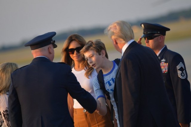First Lady Melania Trump (2L) and US President Donald Trump (2R) watch as their son Barron Trump shakes hands with Col Al Smith who greeted them upon arrival at Andrews Air Force Base in Maryland on June 11, 2017. Trump is returning to Washington, DC after spending the weekend at this Bedminster, New Jersey golf club. / AFP PHOTO / MANDEL NGAN